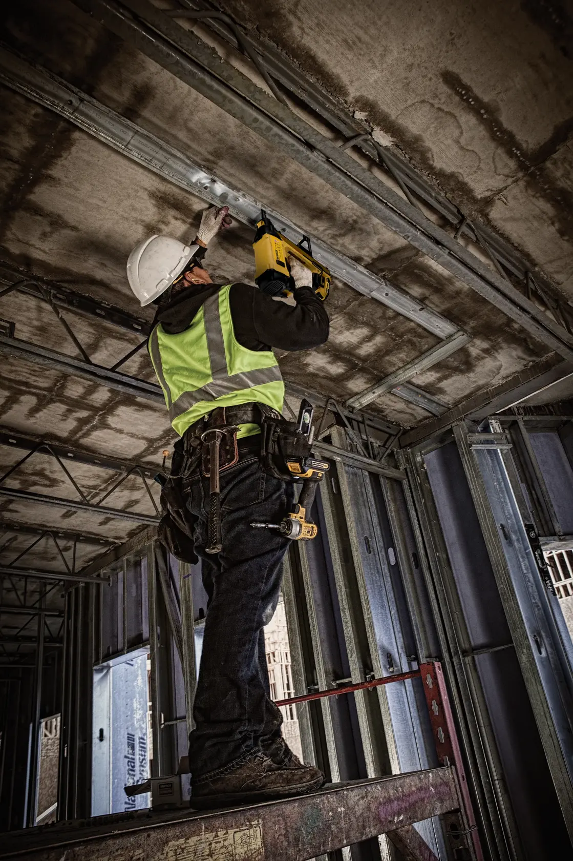 Worker uses DEWALT DGN845D1-QW and DGN845D1 tool on industrial floor, wearing safety gear. Photography product.