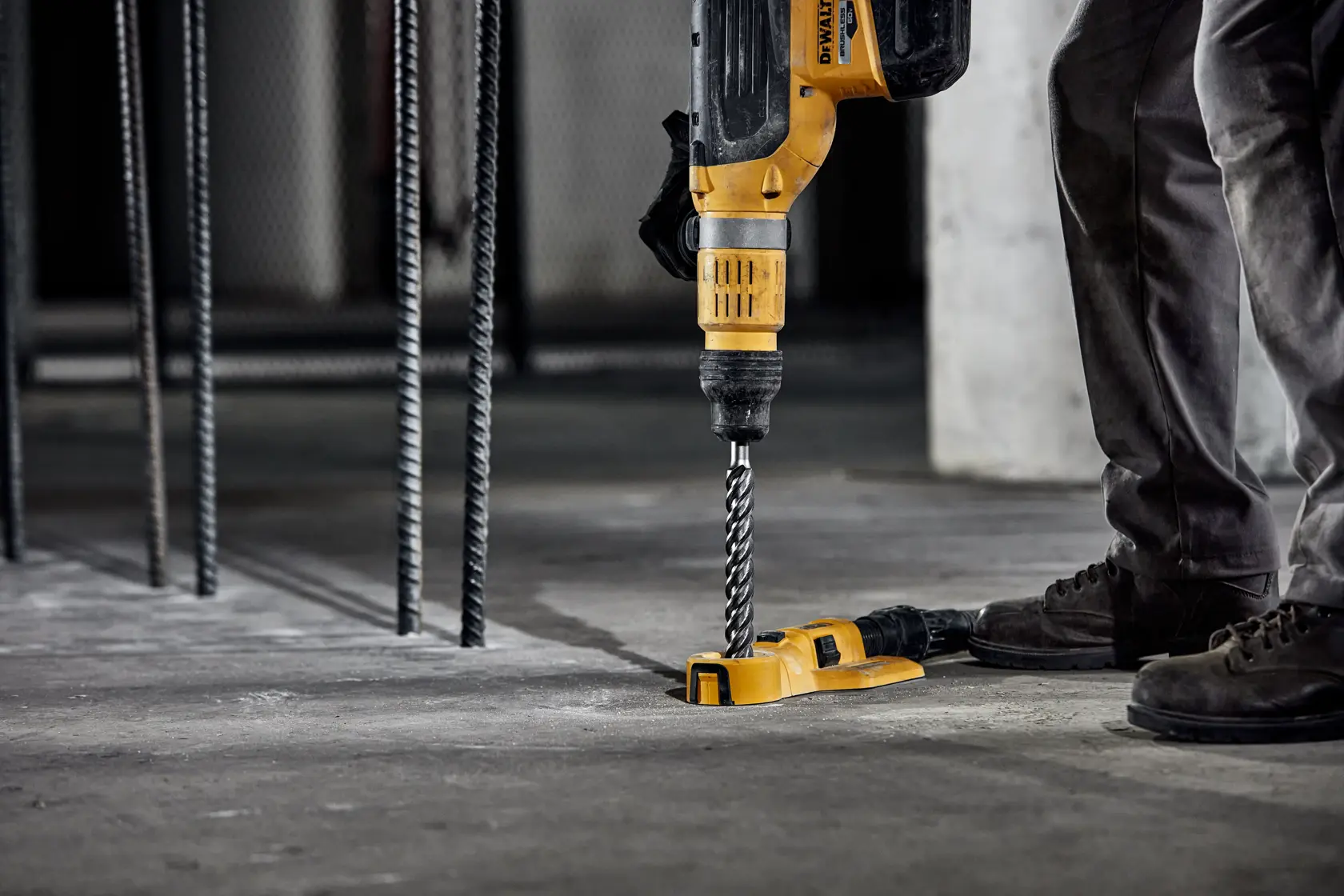 Persona usando martillo perforador DEWALT con broca en piso de concreto de construcción.