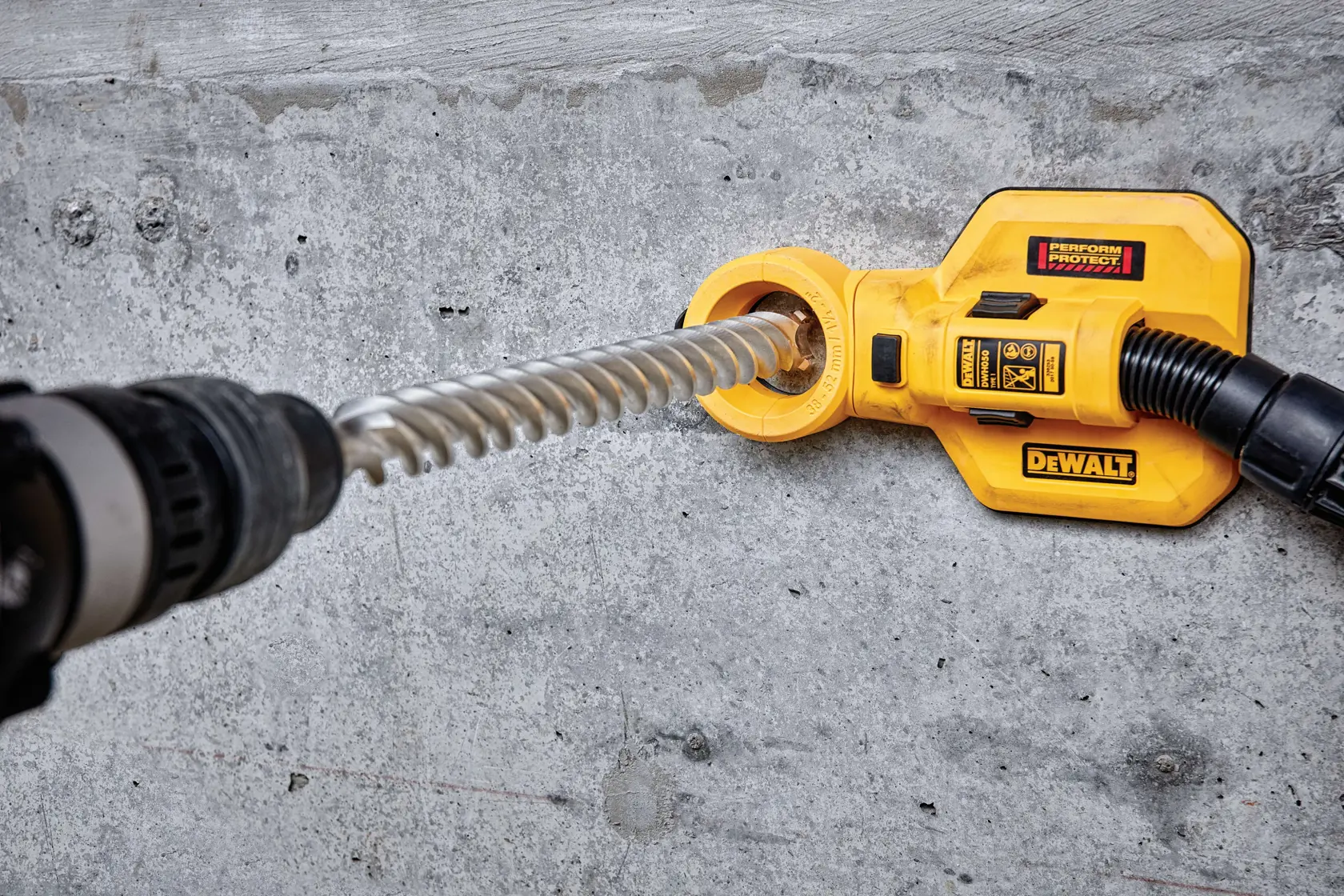Accesorio extractor de polvo DEWALT usado con taladro en pared de concreto.