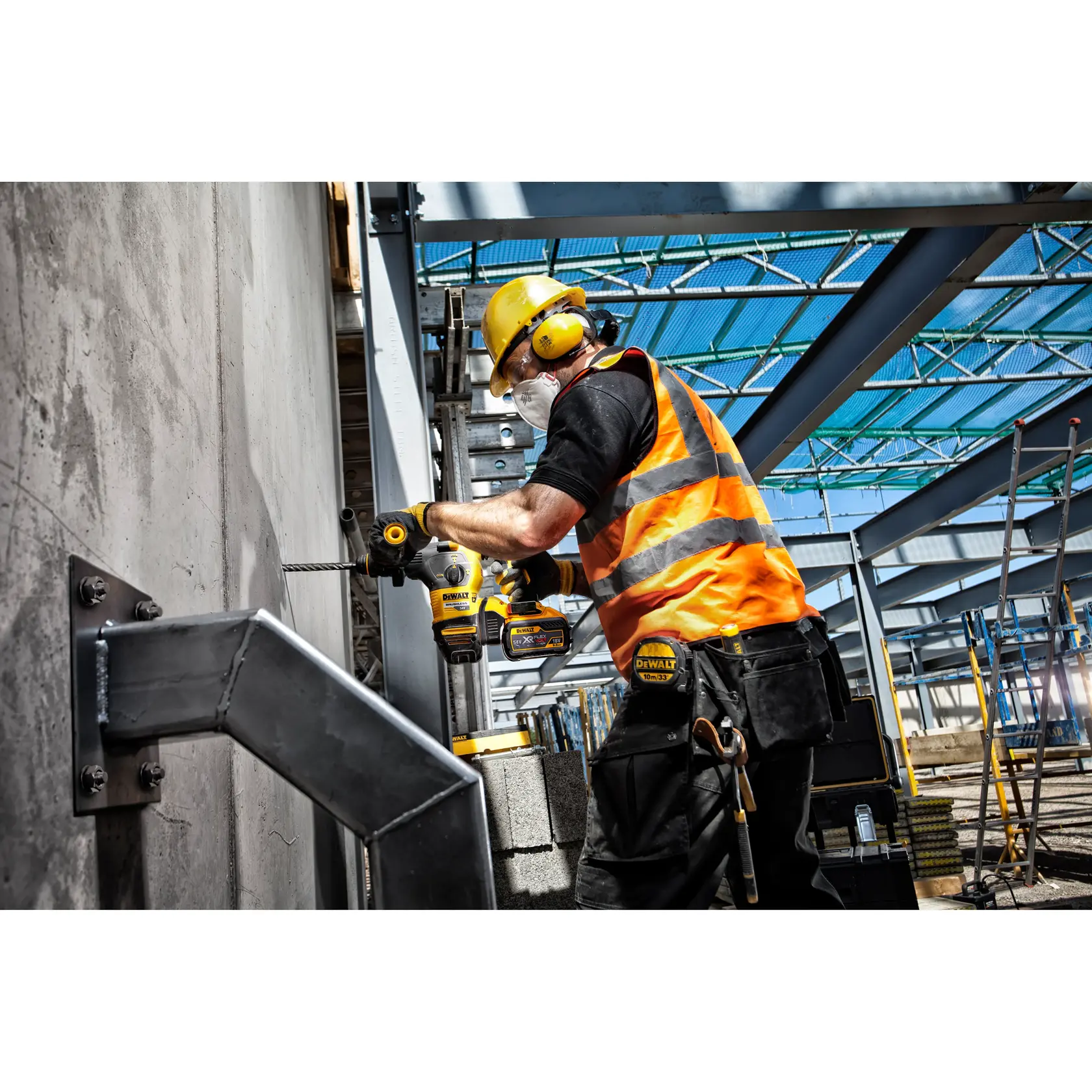 Persona taladra pared de cemento con herramienta DEWALT en obra, usando equipo de seguridad.