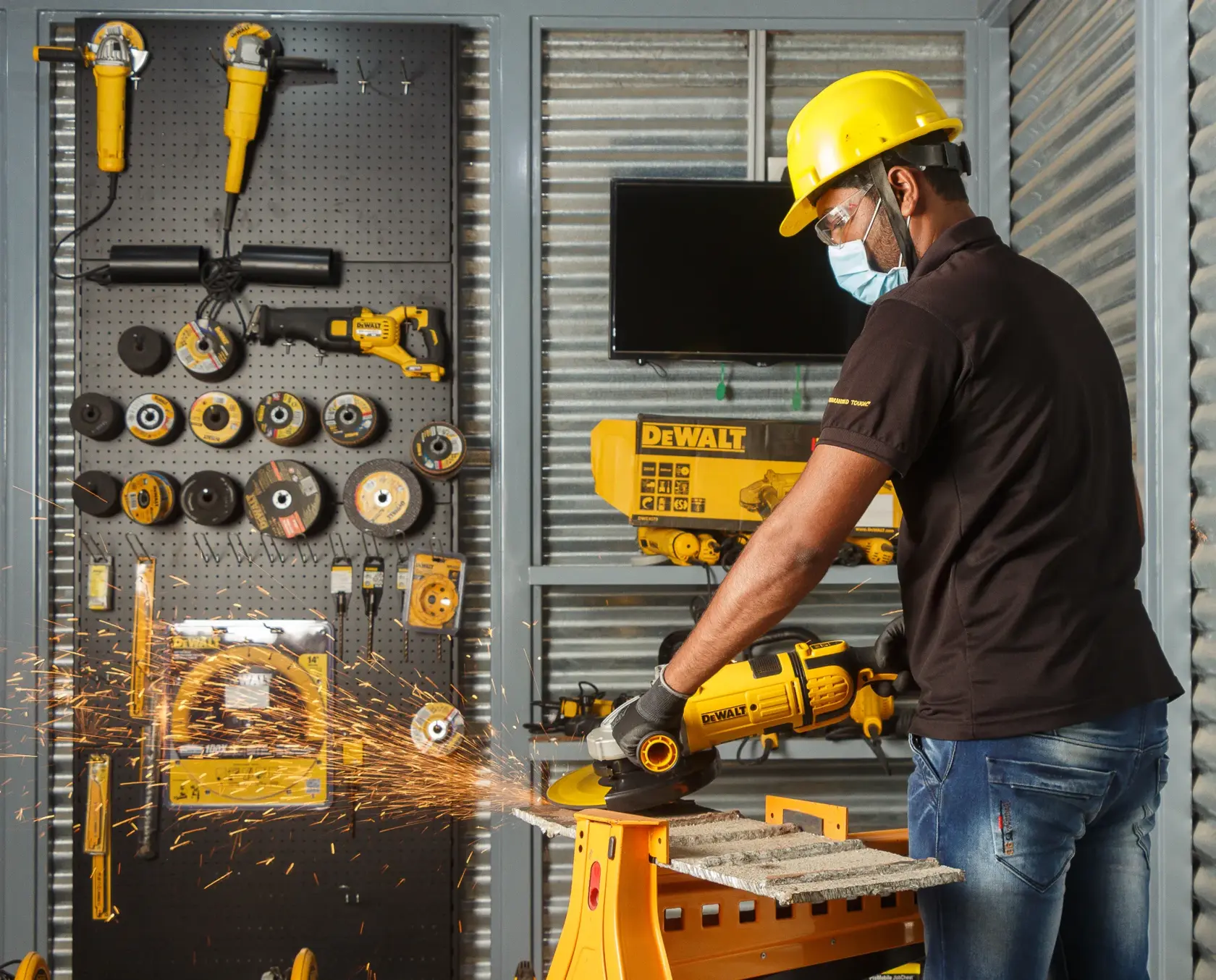 Persona corta metal con herramienta DEWALT, saltan chispas. Herramientas organizadas al fondo.